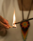 Hand holding a match to light a flame against a blurred background