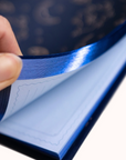 Hand holding a blue reflective material from dream journal against a blurred background