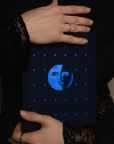 Dream Journal with a sark blue embroidered book with a moon and star design held by hands.