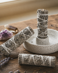 Smudge sticks on a wooden surface with crystals and lavender.