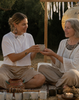 Sharon giving her mother a cup of cacao in a cacao ceremony setting outside