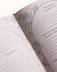 Open journal with angel illustration and writing prompts on a white background
