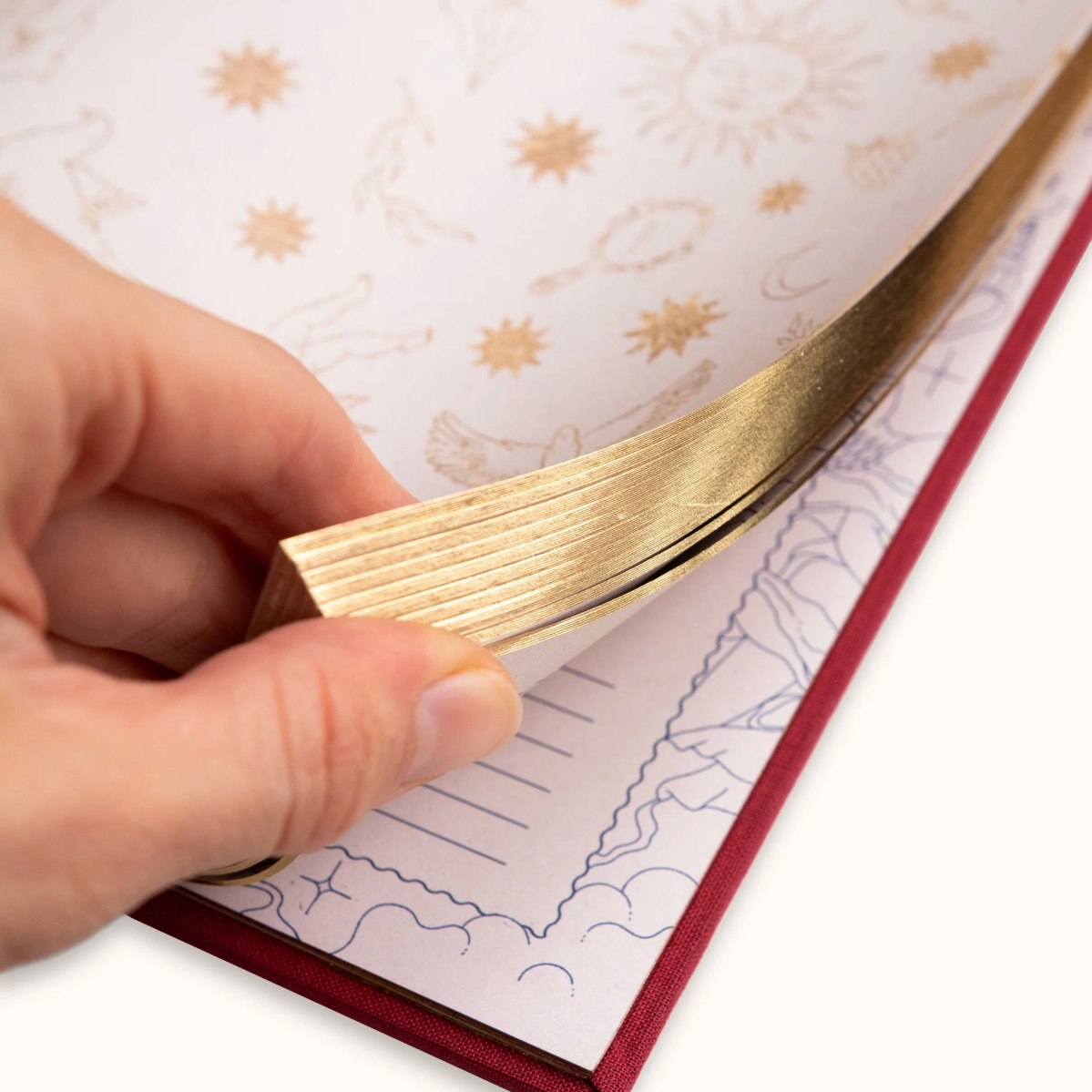 Hand holding a gold journal against a notebook with star pattern