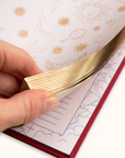 Hand holding a gold journal against a notebook with star pattern