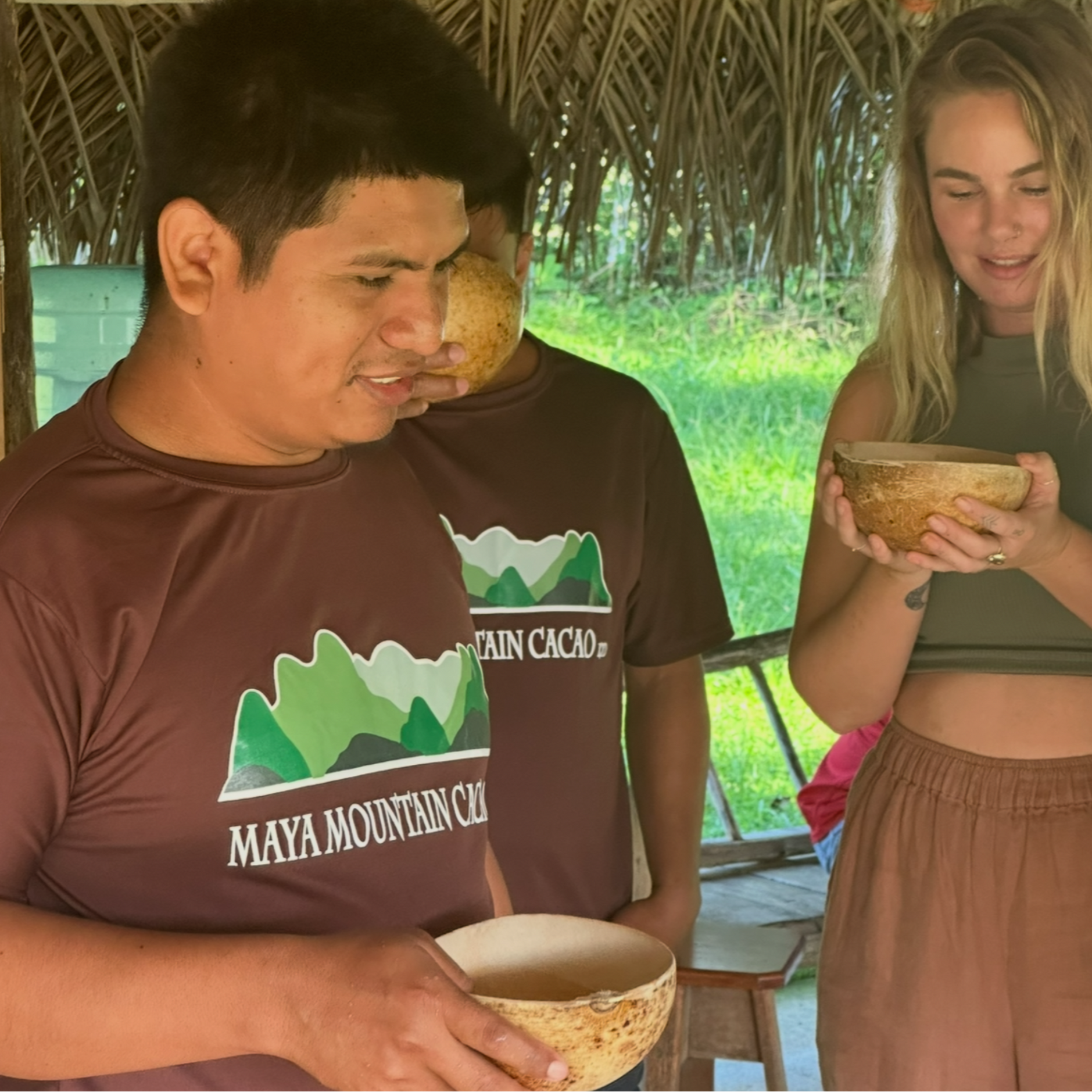 Cacao_Farmer_Maya_Mountain holding coconuts with a natural setting in the background