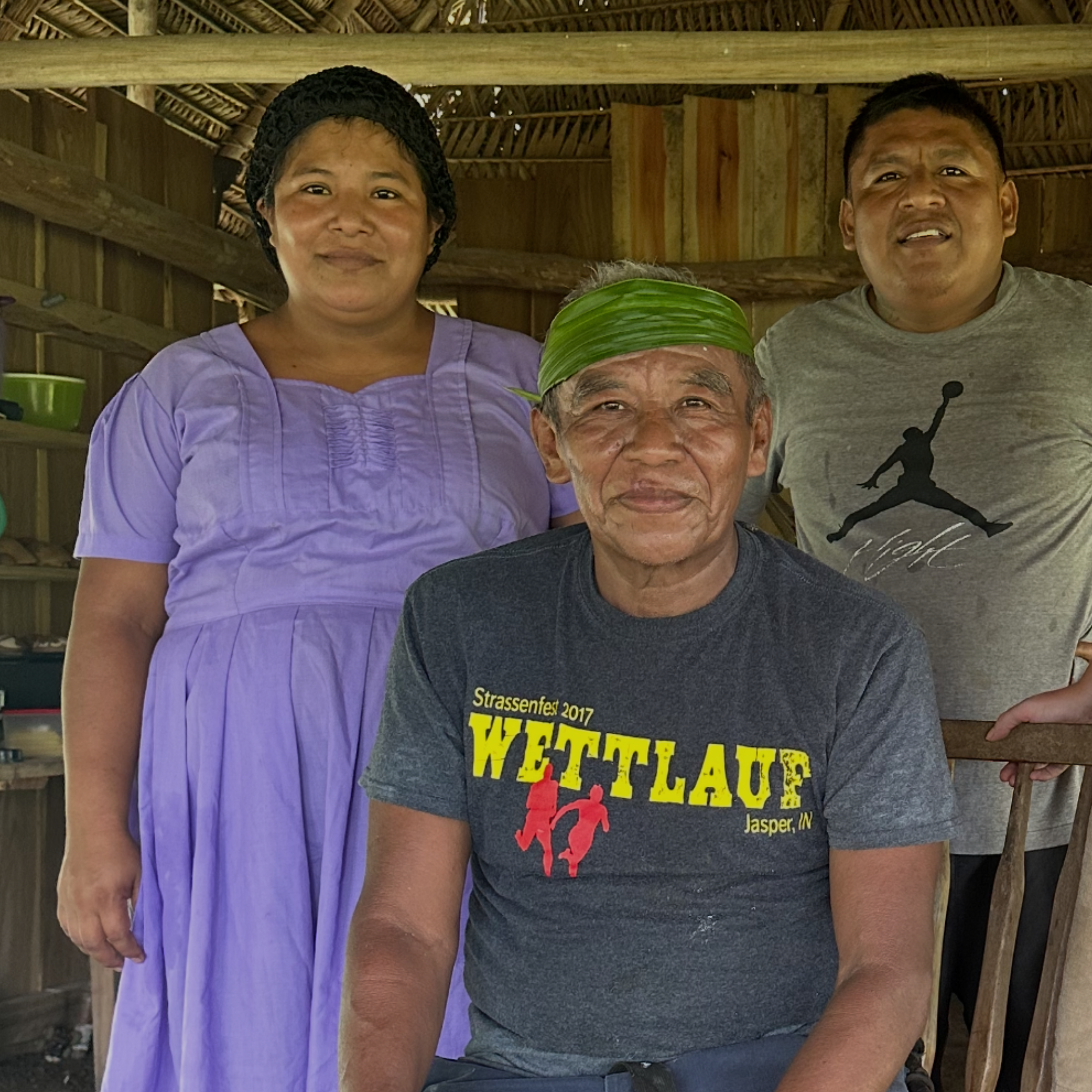 Cacao_Farmer_Maya_Mountain Family standing together indoors with a wooden structure in the background