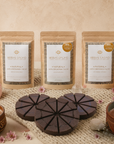 Herbal Cacao products with packaging, chocolate bars, and candles on a textured surface.