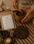 Person holding a cup of cacao with a label for 'Herbal Cacao' on a textured surface.