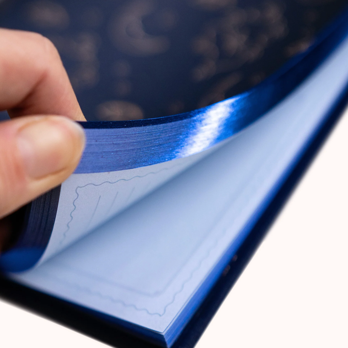 Hand holding a blue reflective material from dream journal against a blurred background
