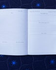Open dream journal with lined pages on a dark blue fabric background with star patterns