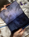 Person holding an dream journal with mystical designs and text on a textured surface.