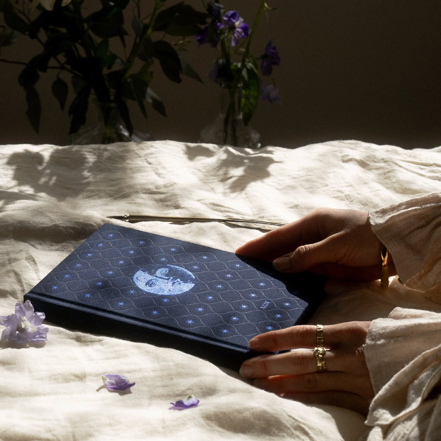 Person holding a dream journal with a white design on a textured surface with flowers.