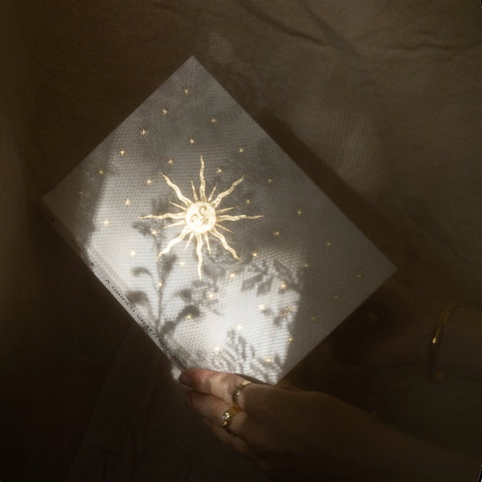 Hand holding a Gratitude Journal with a star design against a dark background
