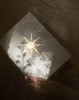 Hand holding a Gratitude Journal with a star design against a dark background