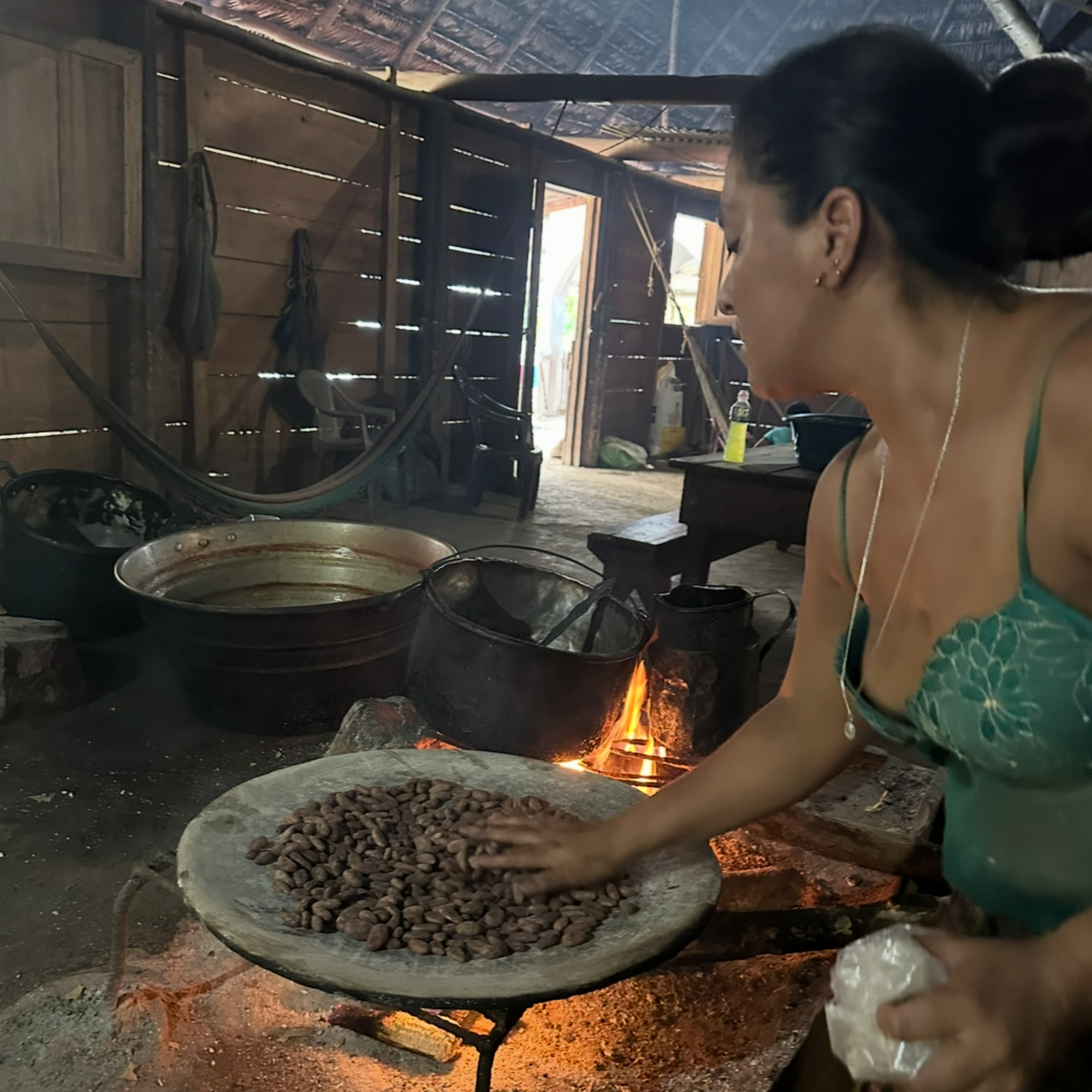 Woman preparing roasting cacao over an open fire in a rustic setting