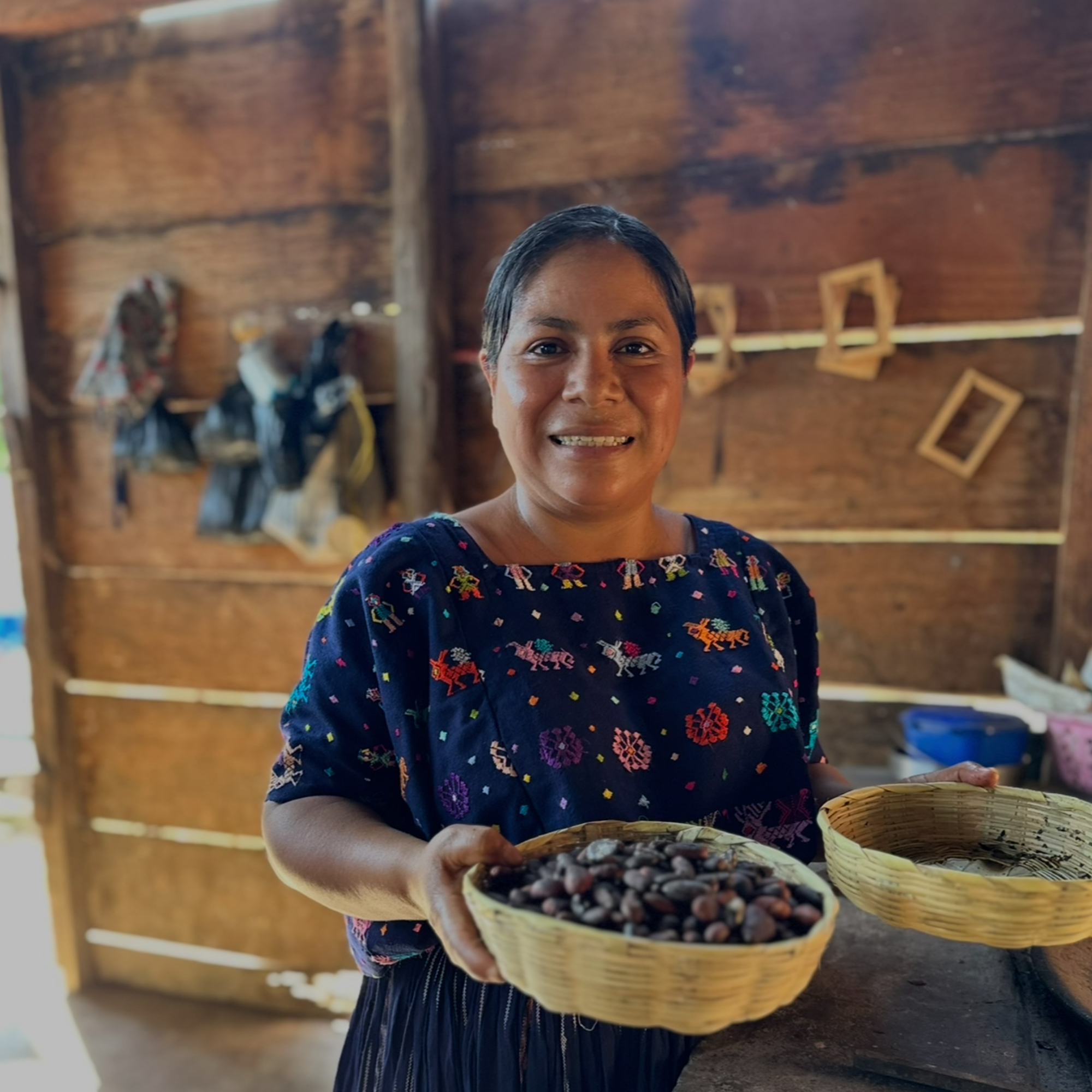 Yasmira holding a bowl of cacao beans in a rustic setting